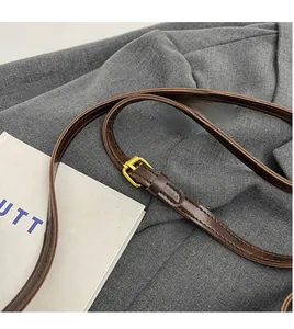 Adjustable brown leather shoulder strap with golden buckle detail on bucket bag