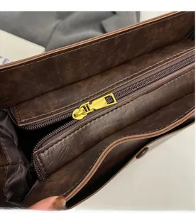 Detail view of smooth golden metal zippers and interior multi-layer compartments in dark brown bag