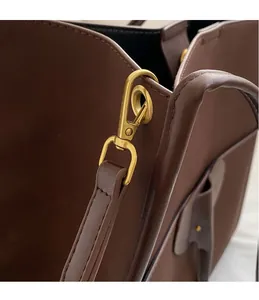 Detail of dark brown matte leather tote with golden metal hook and refined stitching