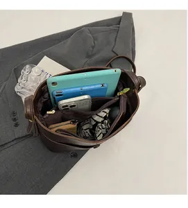 Detail view of large capacity interior with zip compartment in dark brown bucket bag
