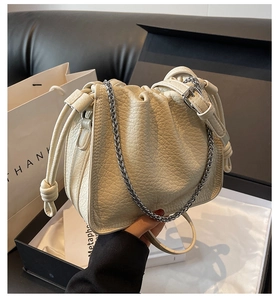 Detail of cream bucket bag showing lychee leather texture and silver chain strap