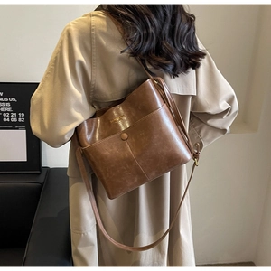 Detail of vintage brown leather bucket bag with front pocket and gold letter branding