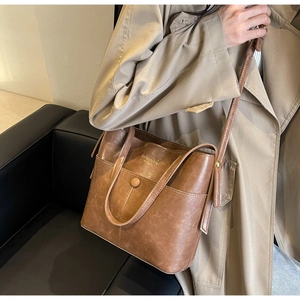 Detail view of a vintage brown bucket bag with gold lettering and decorative front pocket
