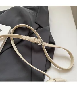 Detail of adjustable beige faux leather shoulder strap with a polished metal buckle