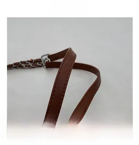 Close-up of the brown leather handle with fine stitching and metal chain connector