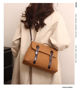 Detail of vintage brown canvas tote bag with leather straps and silver buckle on model