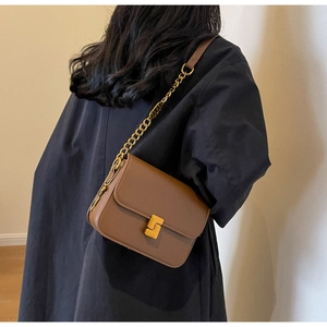 Detail of vintage brown crossbody bag with gold geometric lock and chain strap
