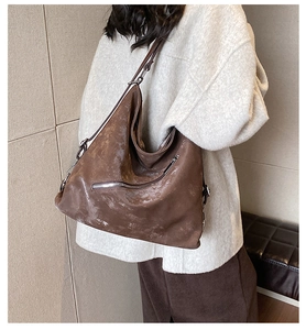 Detail of a large vintage brown oil-wax leather tote bag shown on a model's shoulder