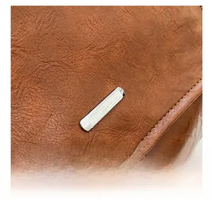 Macro shot of brown pebble grain leather texture with silver metal brand logo plate