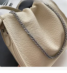 Detailed close-up of beige bucket bag with lychee texture and silver chain strap