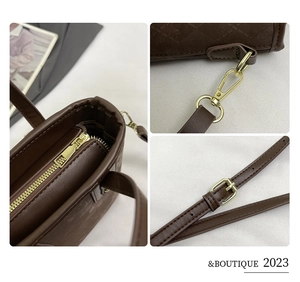 Detail view of dark brown quilted leather bucket bag showing zipper and metal hardware