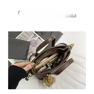 Detail view of large capacity dark brown bucket bag interior with items and gold hardware