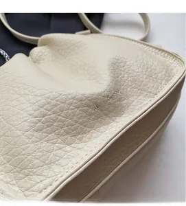 Close-up of off-white bucket bag showing premium lychee pattern leather texture