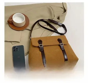 Detail of vintage suede tote bag with brown leather straps and gold buckle accents