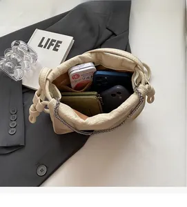 Detail view of the spacious inner compartment of this cream pleated bucket bag with chain