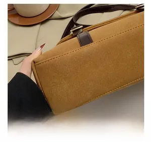 Detailed view of precision stitching on brown suede shoulder bag with gold buckle