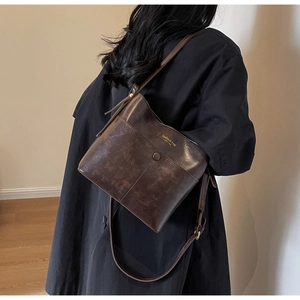 Detail of dark brown vintage bucket bag featuring gold fashion lettering and texture