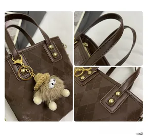 Detail view of coffee argyle bucket bag with gold hardware and plush monster charm