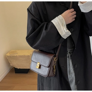 Detail view of vintage dark chocolate leather crossbody bag with gold buckle hardware