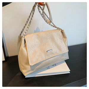 Detail of cream flap shoulder bag featuring a silver rectangular buckle and chain strap
