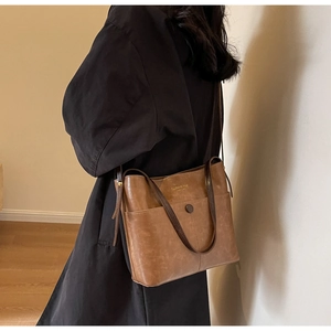 Detail of vintage brown leather bucket bag with front pocket and gold logo lettering
