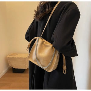 Detail view of khaki leather bucket bag with litchi texture and silver chain