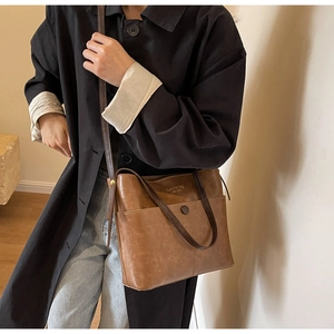 Detail of vintage brown leather bucket bag featuring front pocket and New York logo