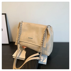 Detail of beige faux leather tote with textured finish and elegant chain shoulder strap