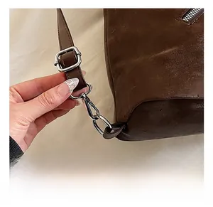 Detail of silver metal lobster clasp and adjustable buckle on dark brown leather bag