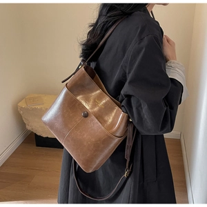 Detail view of brown retro leather bucket bag showing front snap pocket and adjustable strap