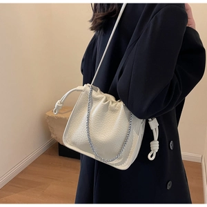 Detail of cream bucket bag showing lychee texture leather and silver chain strap