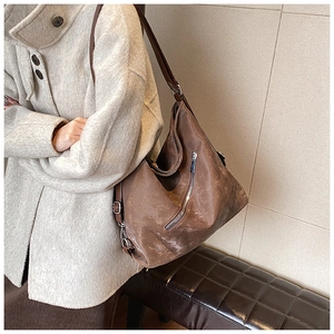 Detail view of brown vintage tote bag with side zipper and metal strap buckle