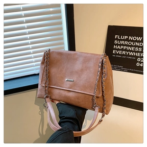 Detail of vintage brown leather tote bag with silver chain strap and pink handles