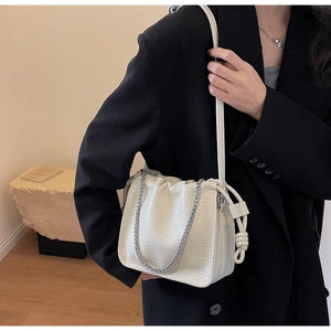 Close-up of cream-colored bucket bag with litchi grain texture and silver chain