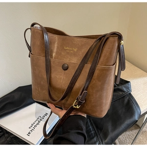 Detail showing vintage brown PU leather texture and gold 'New York' lettering on bucket bag