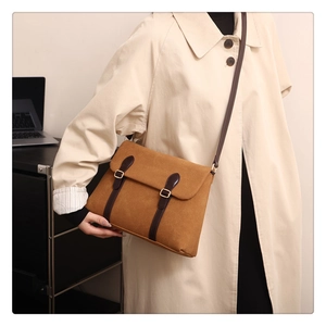Close-up of brown suede crossbody messenger bag with vintage leather straps and buckles