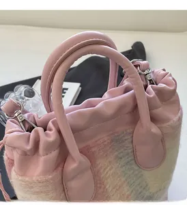 Détail rapproché du sac seau rose avec texture en tweed et crochets argentés polis