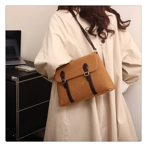 Brown vintage suede tote bag with leather straps and gold buckle shown in a lifestyle office setting