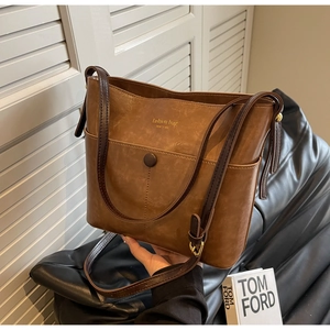 Detail of vintage brown leather bucket bag featuring gold Fashion Bag logo and front pocket
