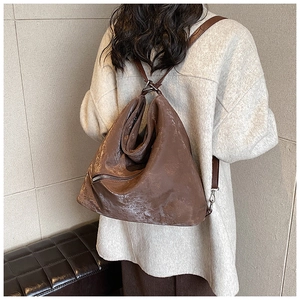 Detail of vintage brown leather backpack showing glossy texture and silver zipper detail