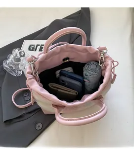 Détail d'un sac seau rose en peluche montrant le rangement interne pour téléphone