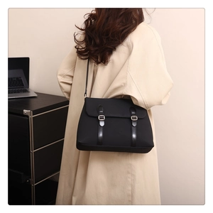 Detail view of a black matte crossbody bag with dual buckles on a model