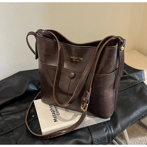 Close-up of vintage dark brown bucket bag with adjustable strap and metallic logo