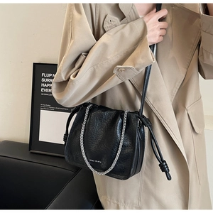 Close-up of black pleated bucket bag with silver metal chain and drawstring detail