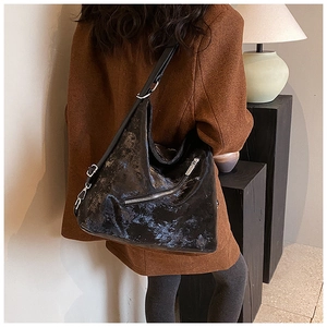 Detail of glossy black tote bag with silver zippers and adjustable shoulder strap