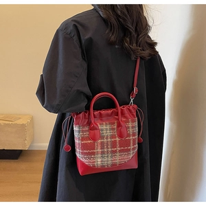 Détail du sac seau à carreaux rouge et bleu avec cordon en cuir et bandoulière réglable