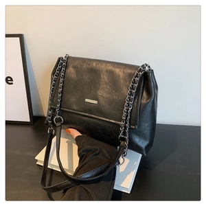Detailed view of the black wrinkled leather texture and silver metal chain strap on tote
