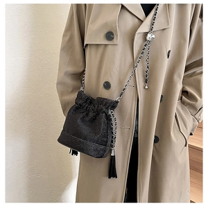 Close-up of black sequin bucket bag with metal chain strap and tassel details