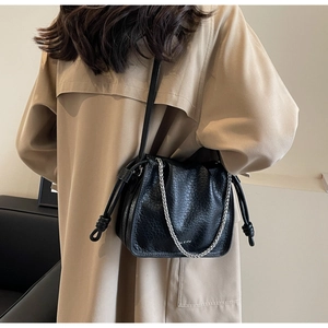 Close-up of black leather bucket bag with silver chain detail and pleated design