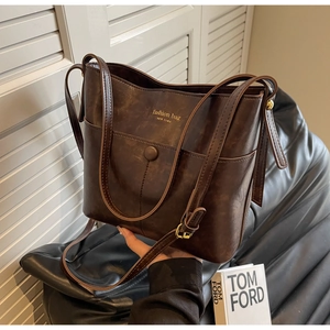 Detailed close-up of dark brown vintage faux leather bucket bag texture and gold foil logo